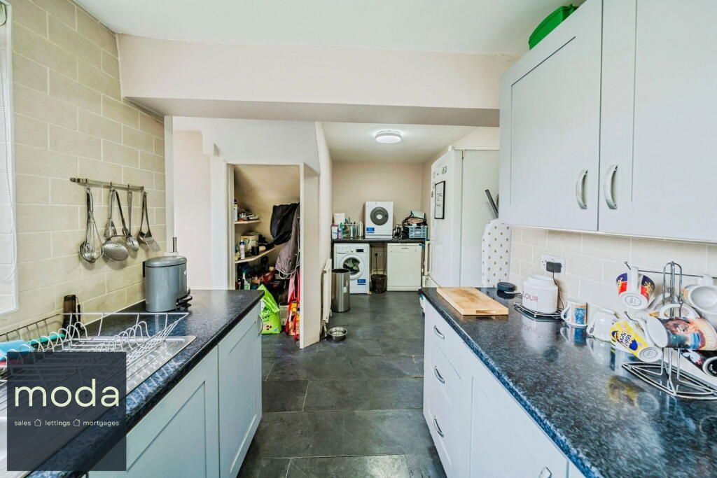 Kitchen with gray cabinets, black countertops, and a doorway to a utility area.