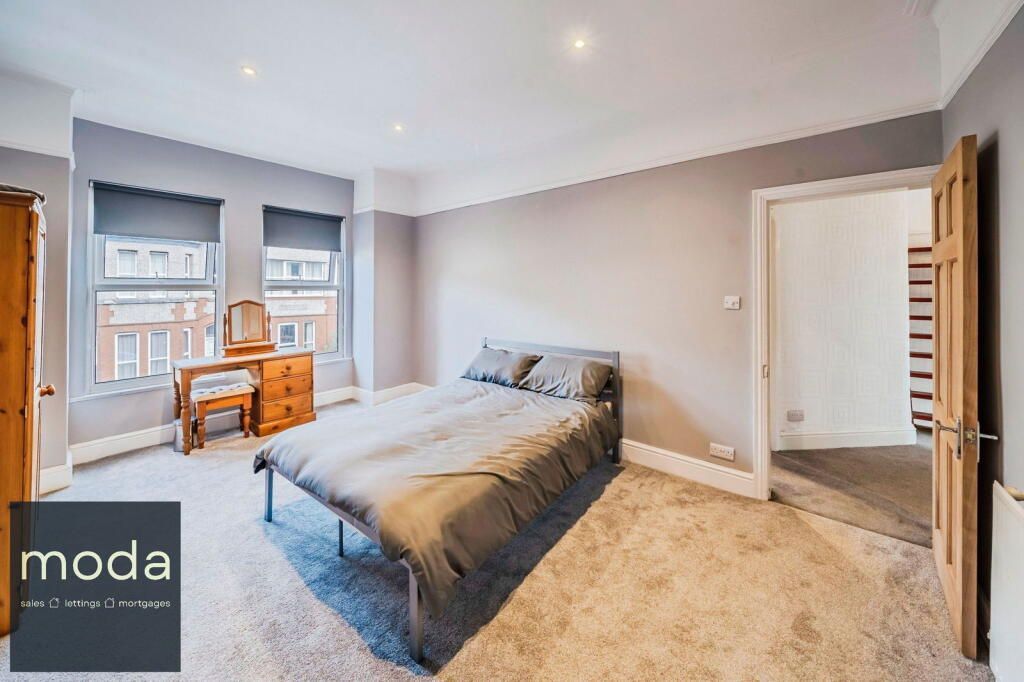 Bedroom with bed, dresser, and open doorway, grey walls, carpet, and windows.