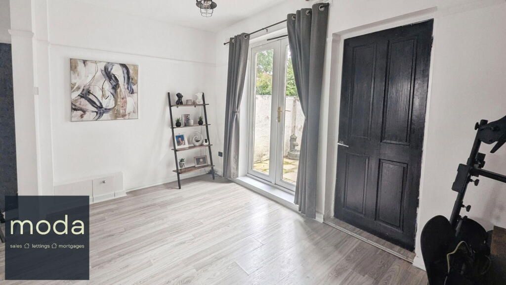 Empty room with a gray floor, white walls, black door, and gray curtains. A small metal shelf stands near the window.