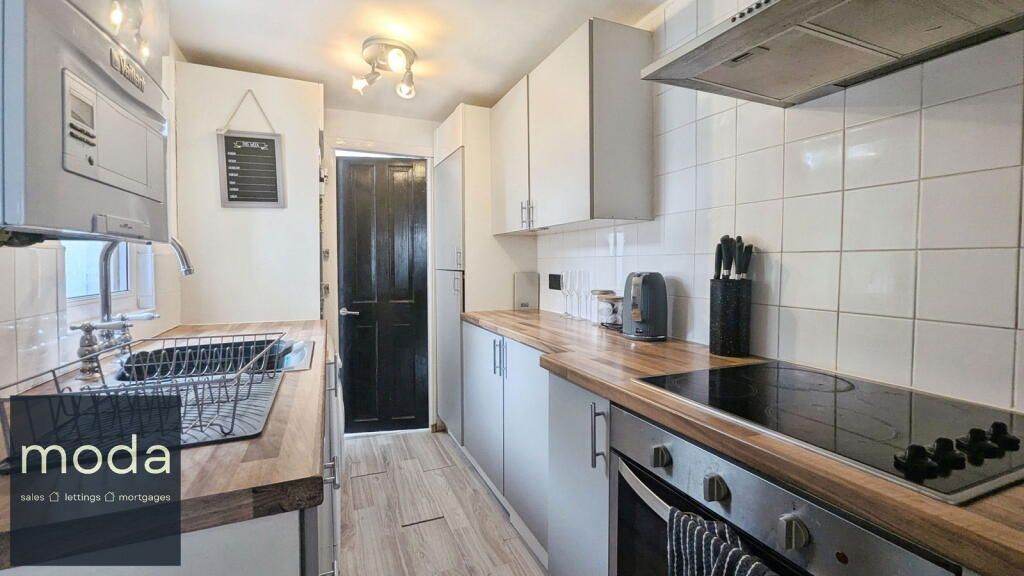 Small kitchen with white cabinets, wood countertops, and stainless steel appliances.