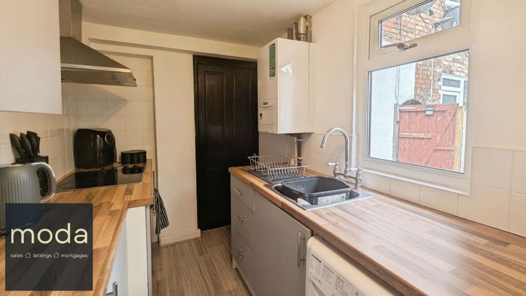 Small kitchen with wooden countertops, gray cabinets, and a window with a view.