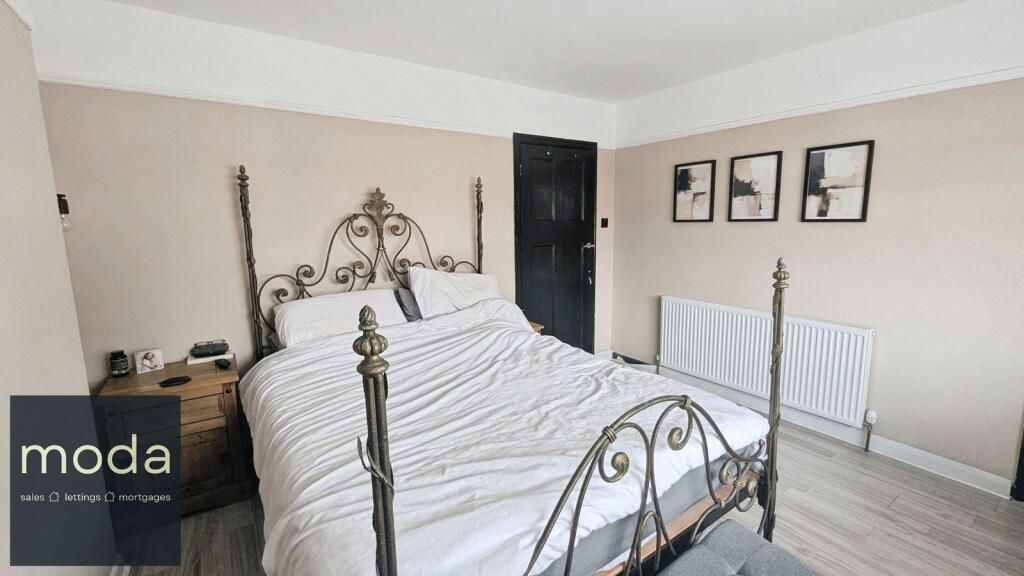 Bedroom with metal bed frame, nightstand, art, and radiator.