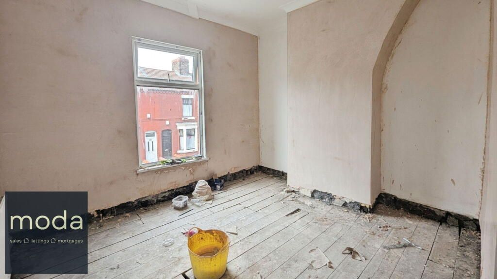 A room under renovation with exposed floorboards, fresh plaster, a window with a street view, and a yellow bucket.