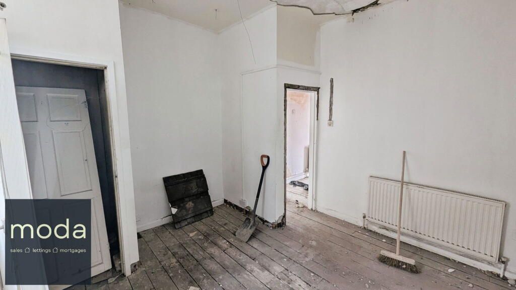 A room being renovated, with exposed floorboards, white walls, and tools scattered about.