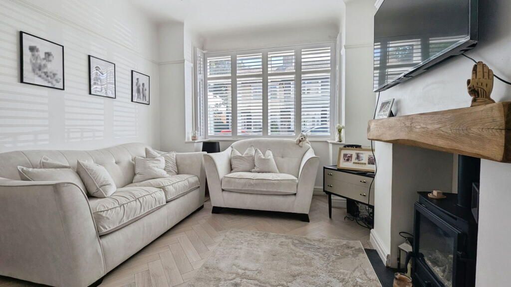 Living room with white brick wall, sofas, fireplace, TV, and window.