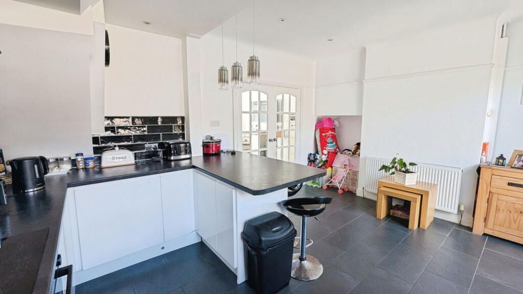 Modern kitchen with white cabinets, black countertops, island, and french doors.