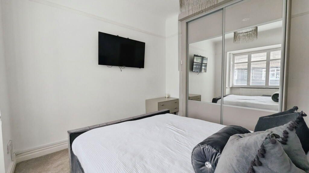 Bedroom with bed, TV, mirrored closet, and nightstand.