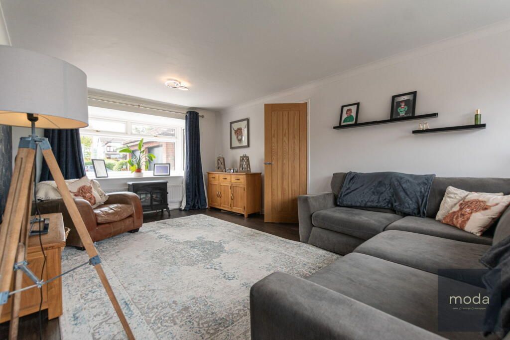 Living room with gray sectional sofa, wooden floor, and large rug.