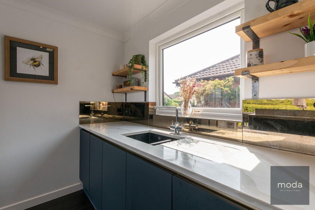 Modern kitchen with blue cabinets, gold backsplash, and wooden shelves.