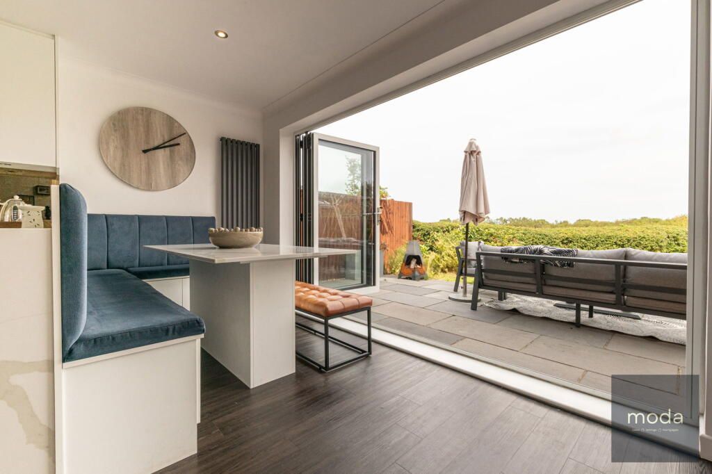 Interior with a dining area, blue seating, and an open door to an outdoor patio.
