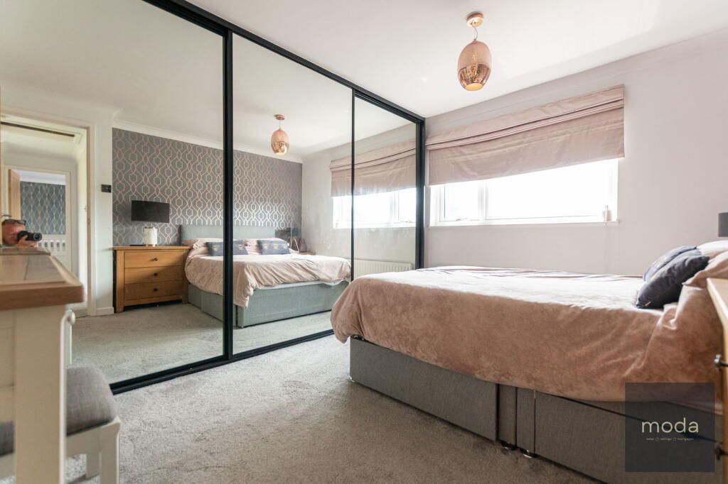 Bedroom with mirrored sliding closet doors, a bed, and neutral colors.