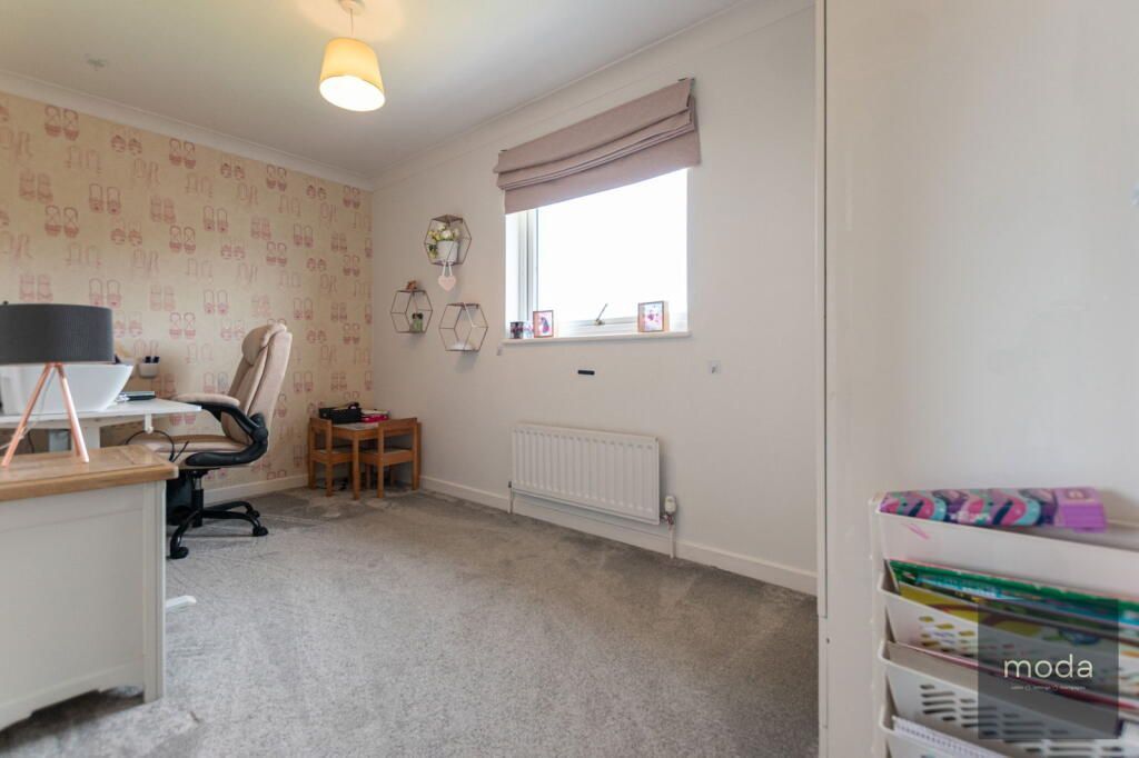 Bedroom with desk, window, and children's table set against neutral walls and carpet.