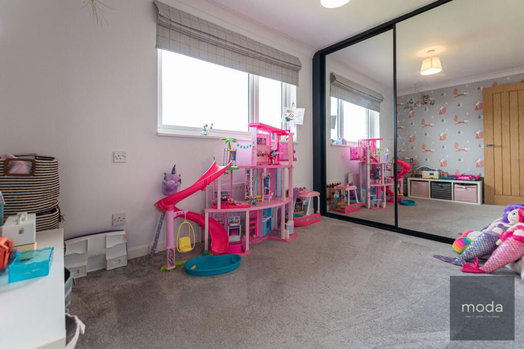 A child's bedroom with toys, large mirror, window, and flamingo wallpaper.