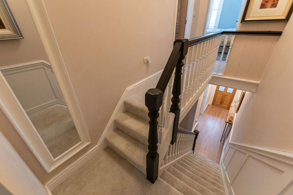 Staircase with carpet steps, dark wood handrails, and a large mirror.