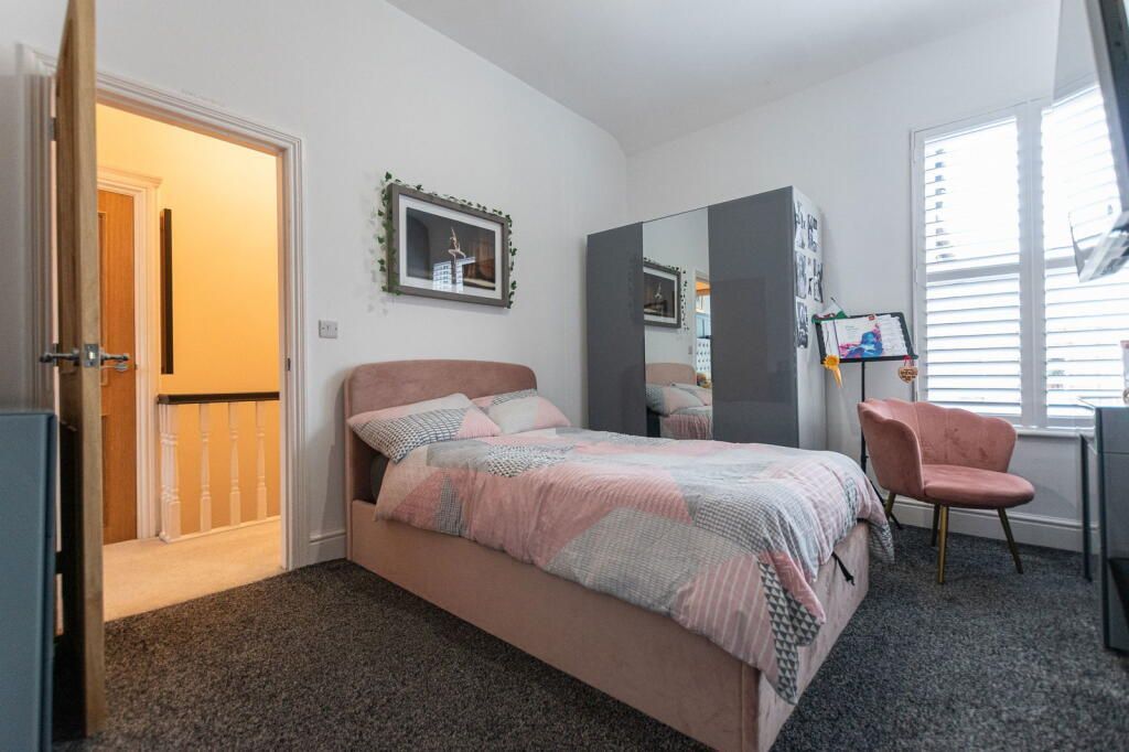 Bedroom with bed, wardrobe, chair, window, and open doorway to a hallway.