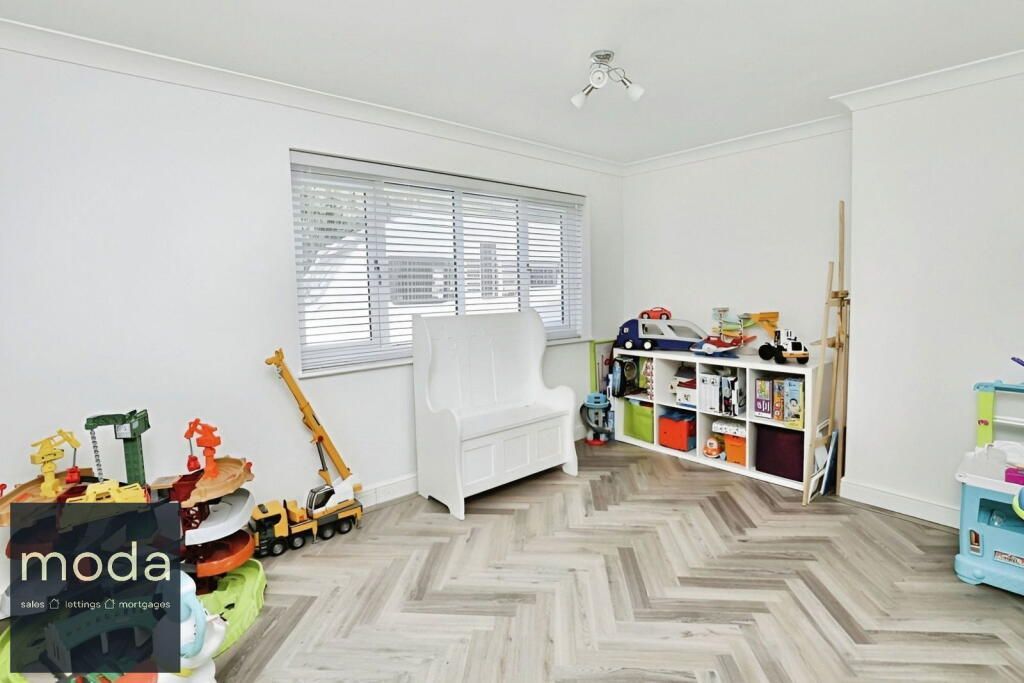 Playroom with white walls, herringbone floor, window, toy shelves, and toys.