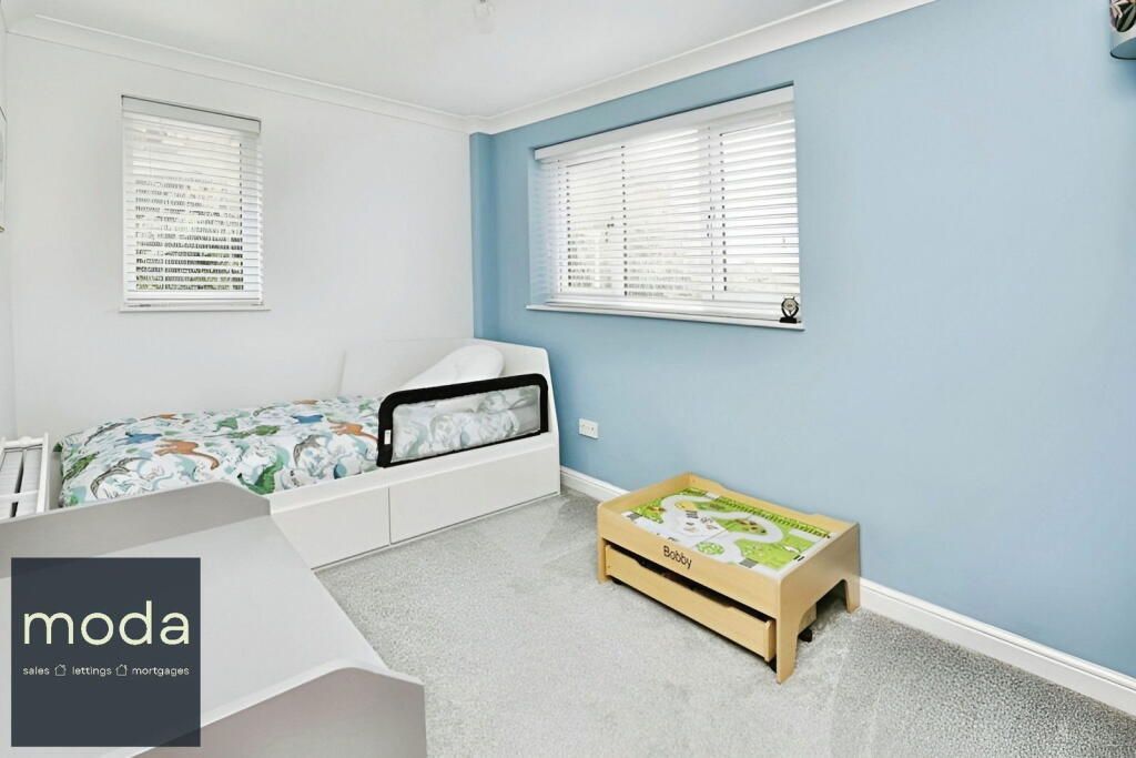 Blue bedroom with a bed, window, and toy table.