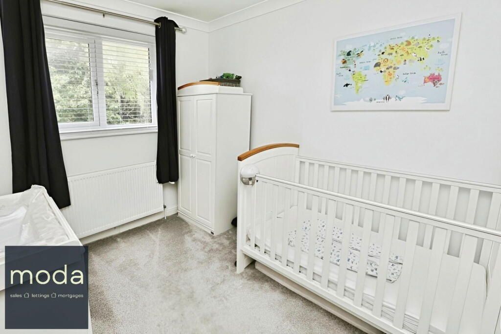 White nursery with crib, map, and wardrobe; window with black curtains.