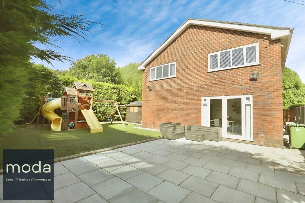 Brick house with patio, playset in yard, sunny day.