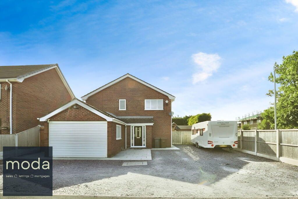Brick house with garage and driveway, RV parked on the drive. Blue sky.