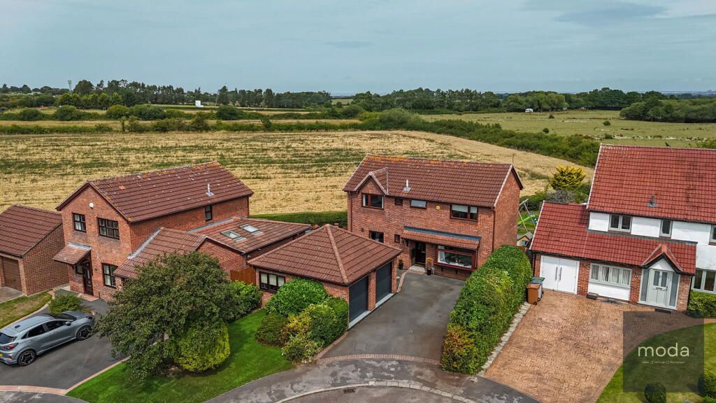 Houses with red roofs and brick exteriors in a rural setting.
