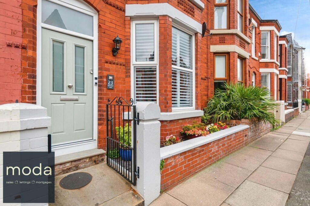 Red brick house exterior with a gray door and wrought-iron gate.