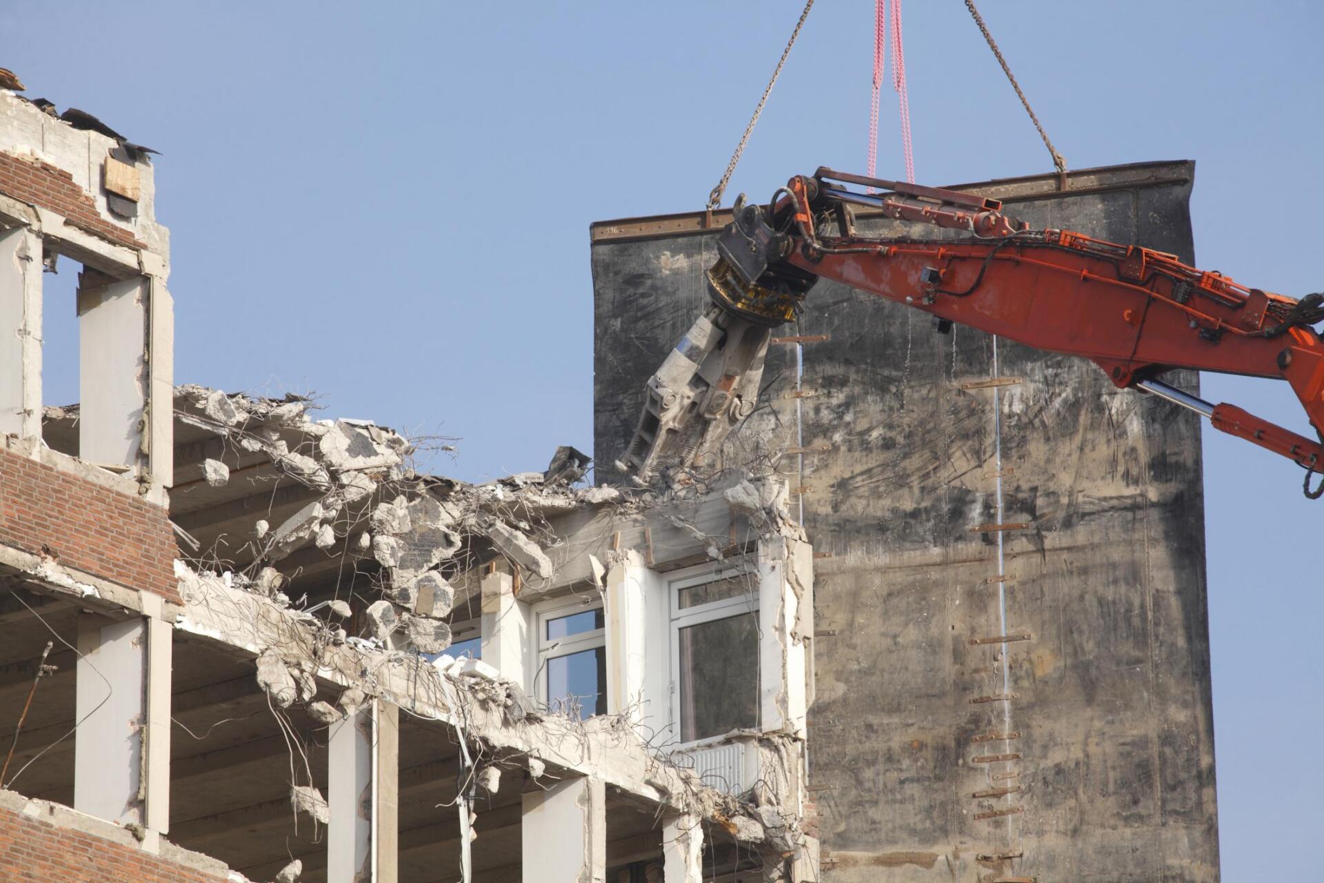 building being demolished by excavator