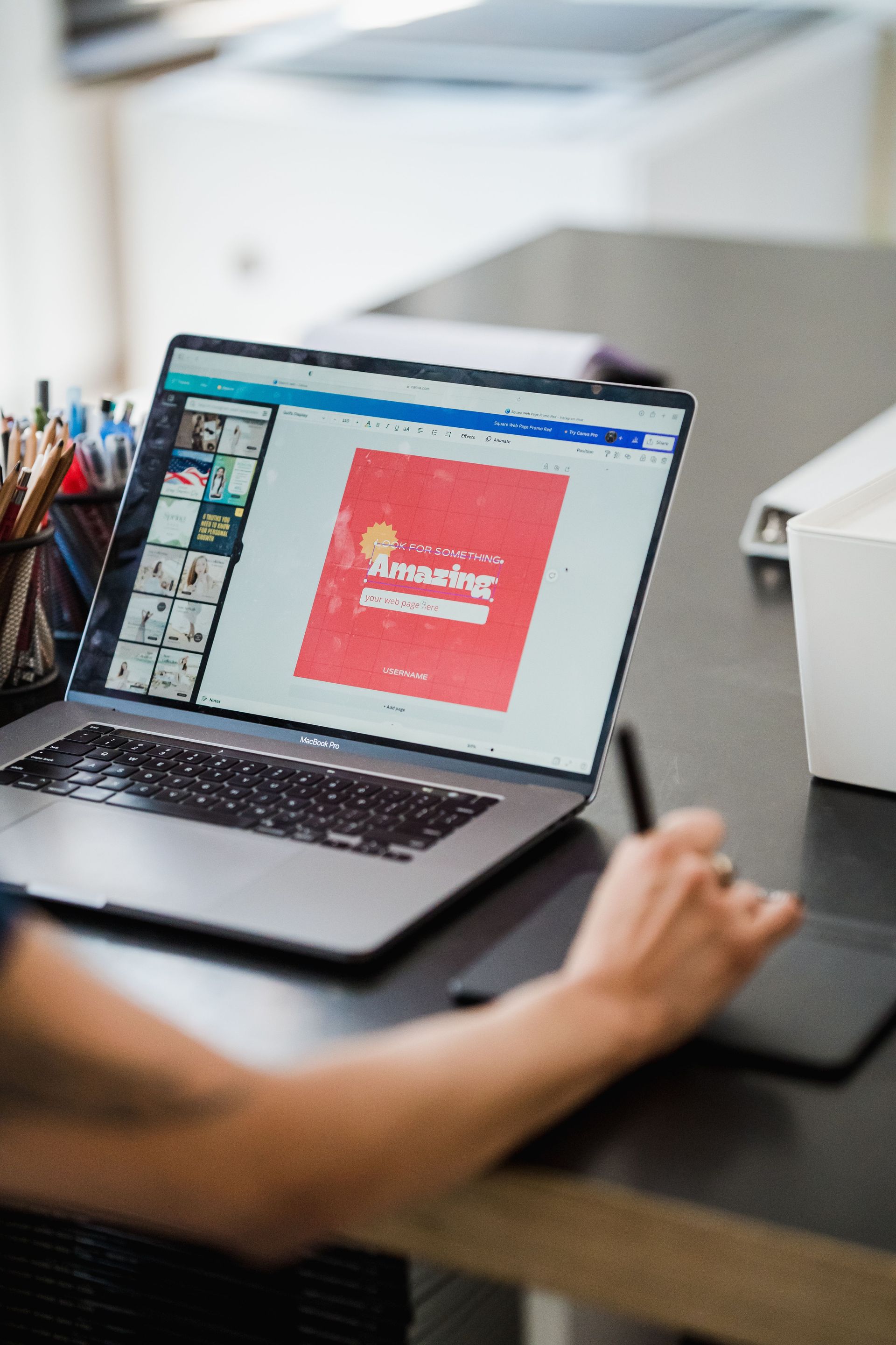 Person using a laptop at a desk with a design app open on screen