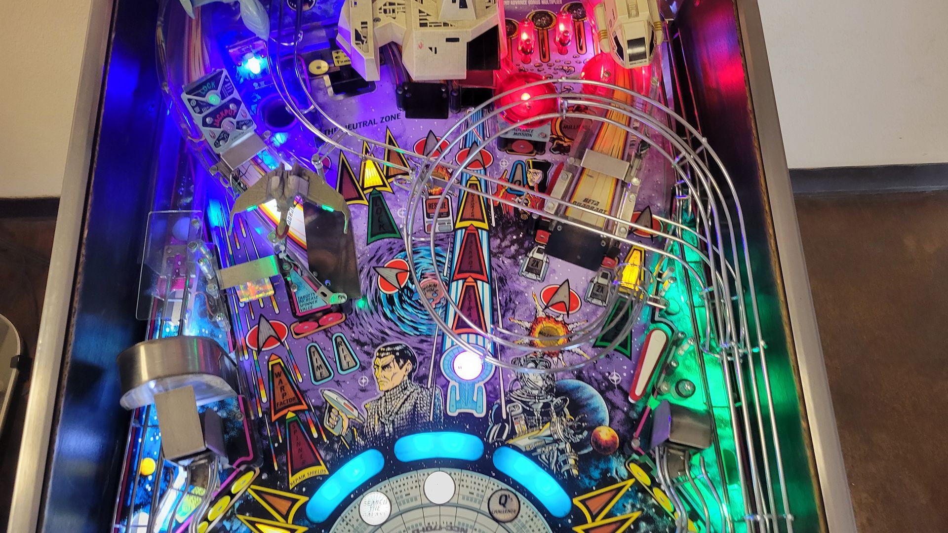 A pinball machine is sitting on a wooden floor in a room.