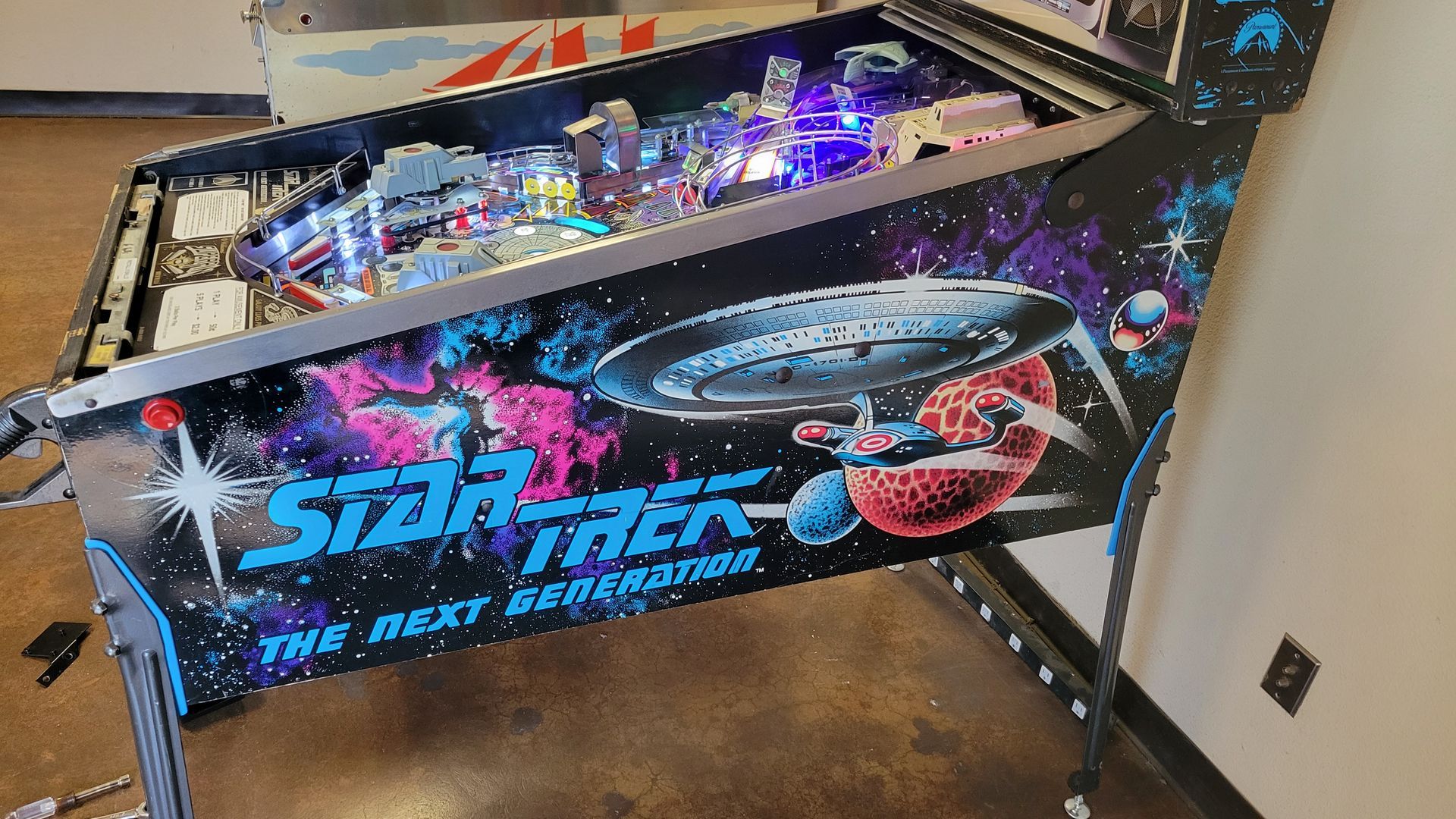 A star trek pinball machine is sitting on the floor in a room.