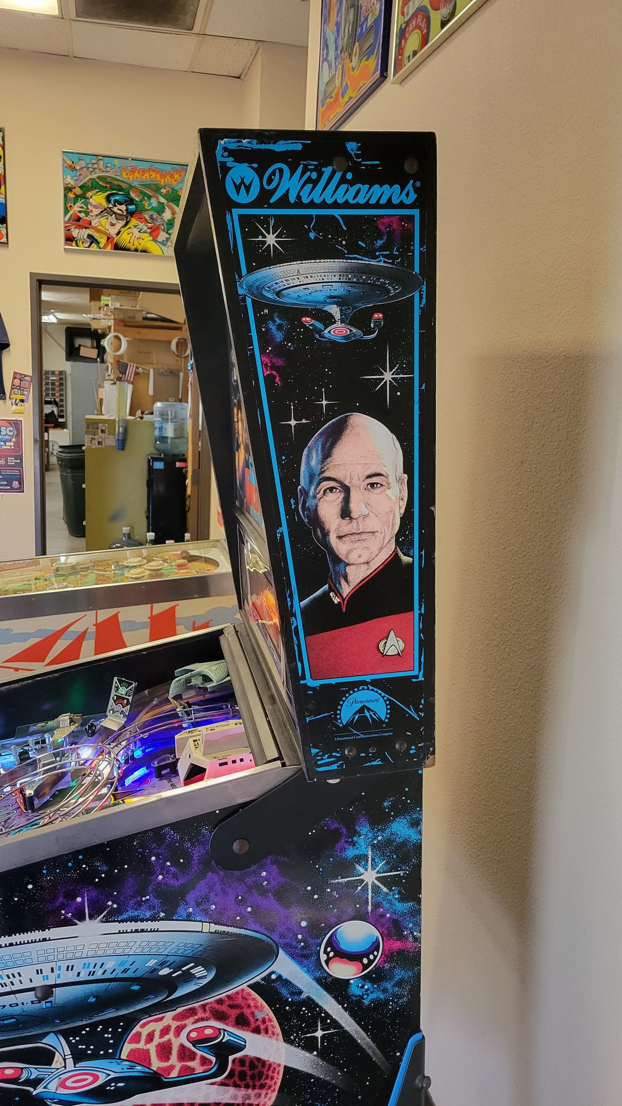 A pinball machine with a picture of a man on it is hanging on a wall.