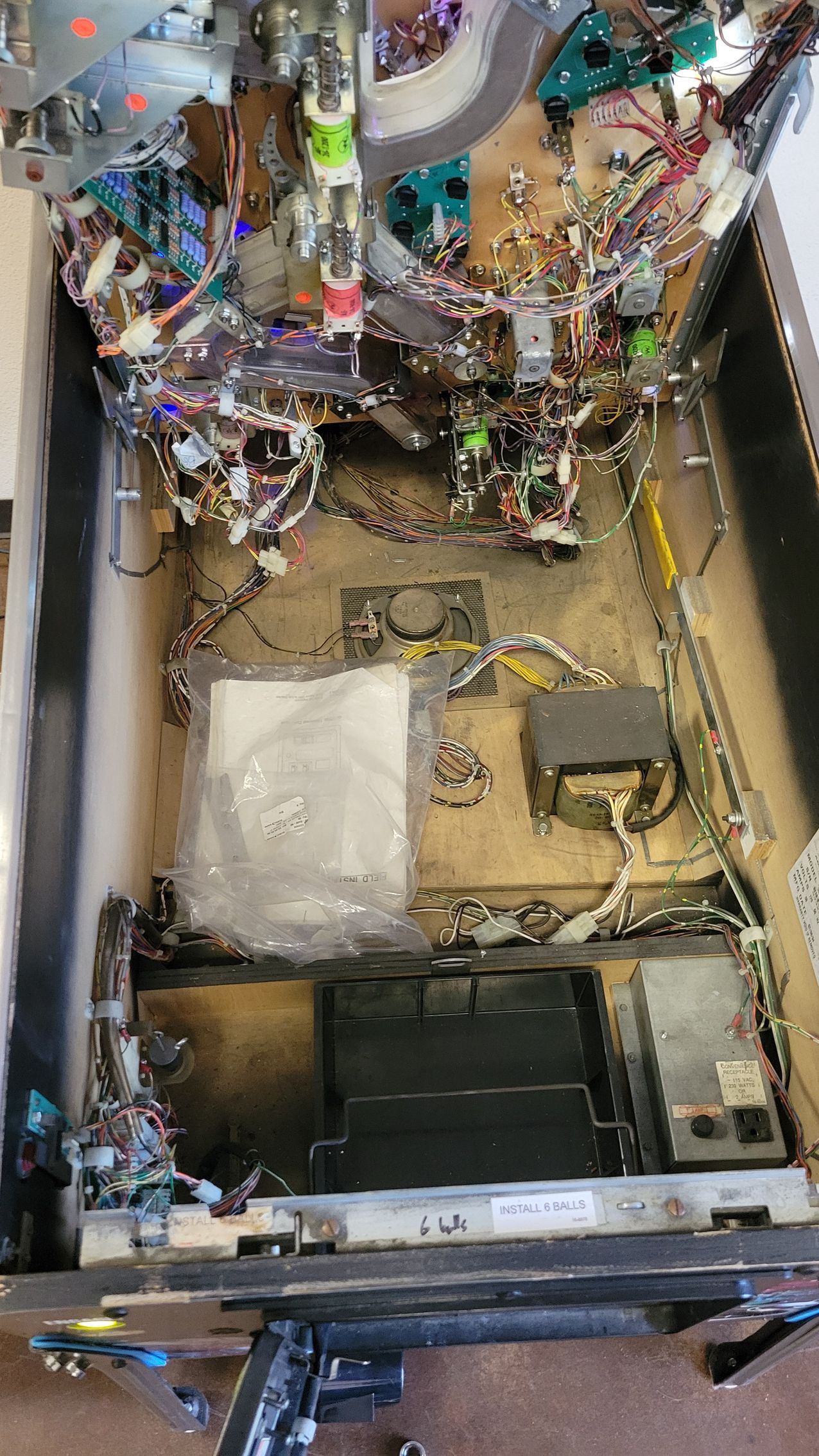 The inside of a pinball machine with a lot of wires coming out of it.