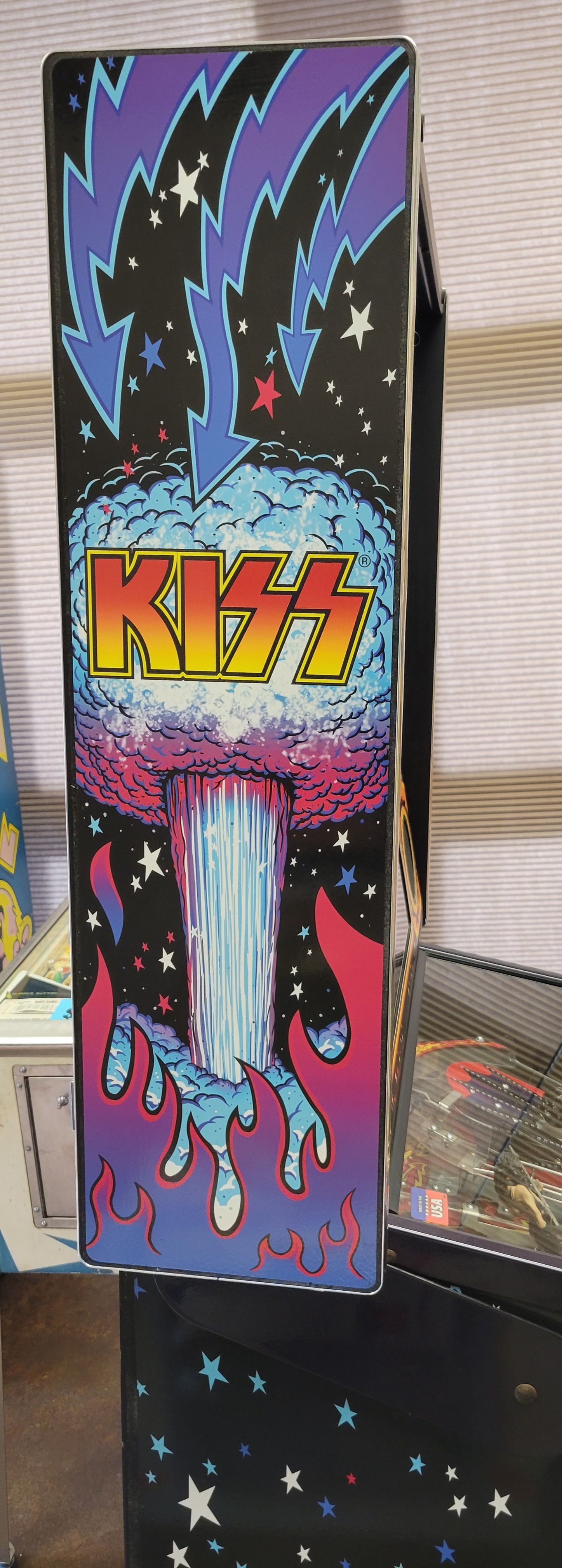 A kiss pinball machine is sitting on a table.
