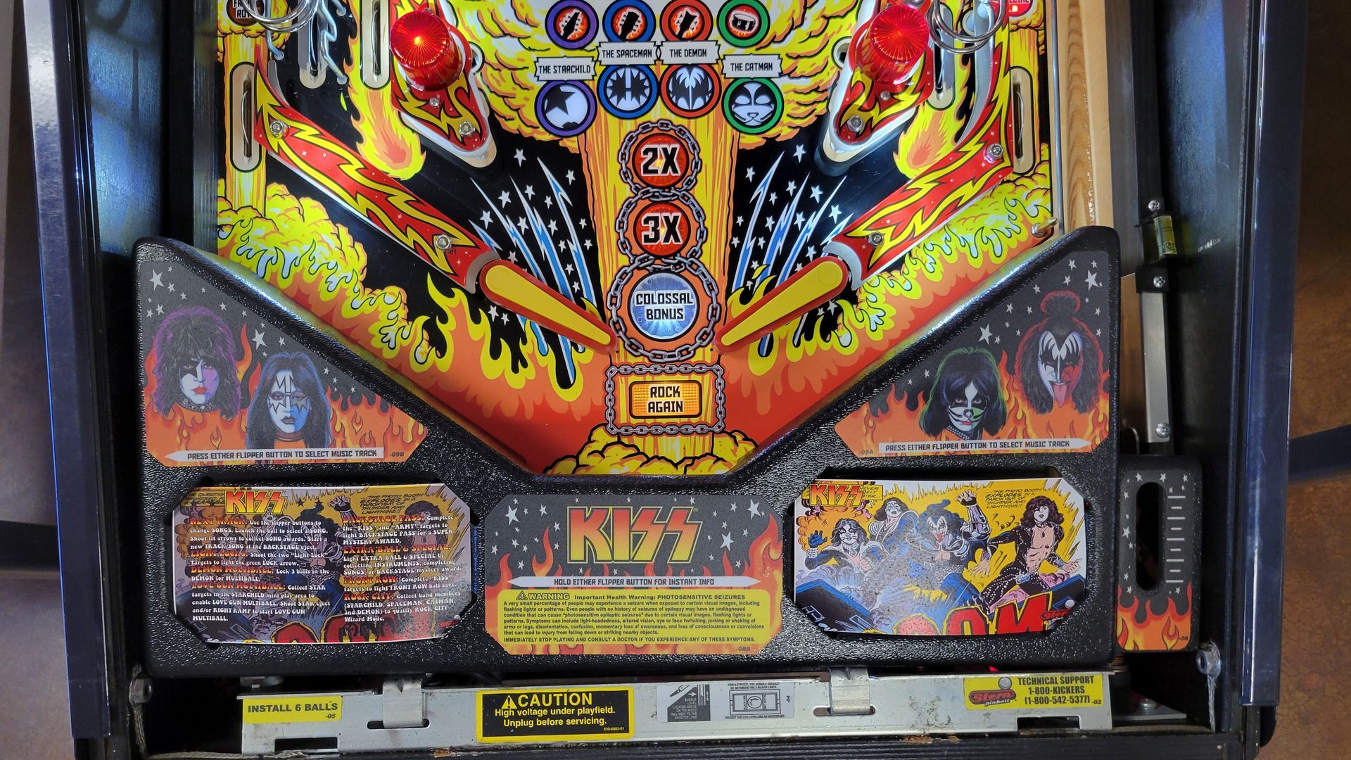 A kiss pinball machine is sitting on a wooden table