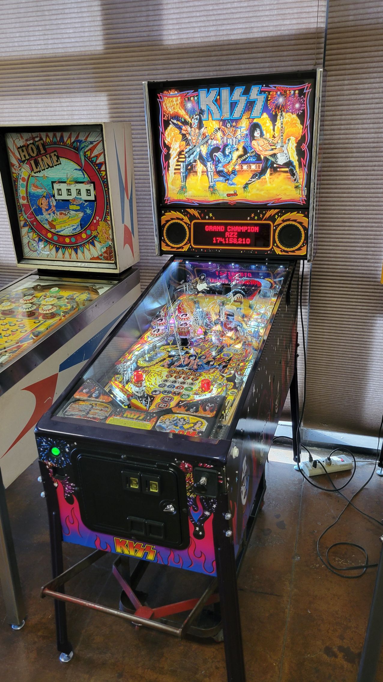 A pinball machine is sitting on a wooden floor next to another pinball machine.
