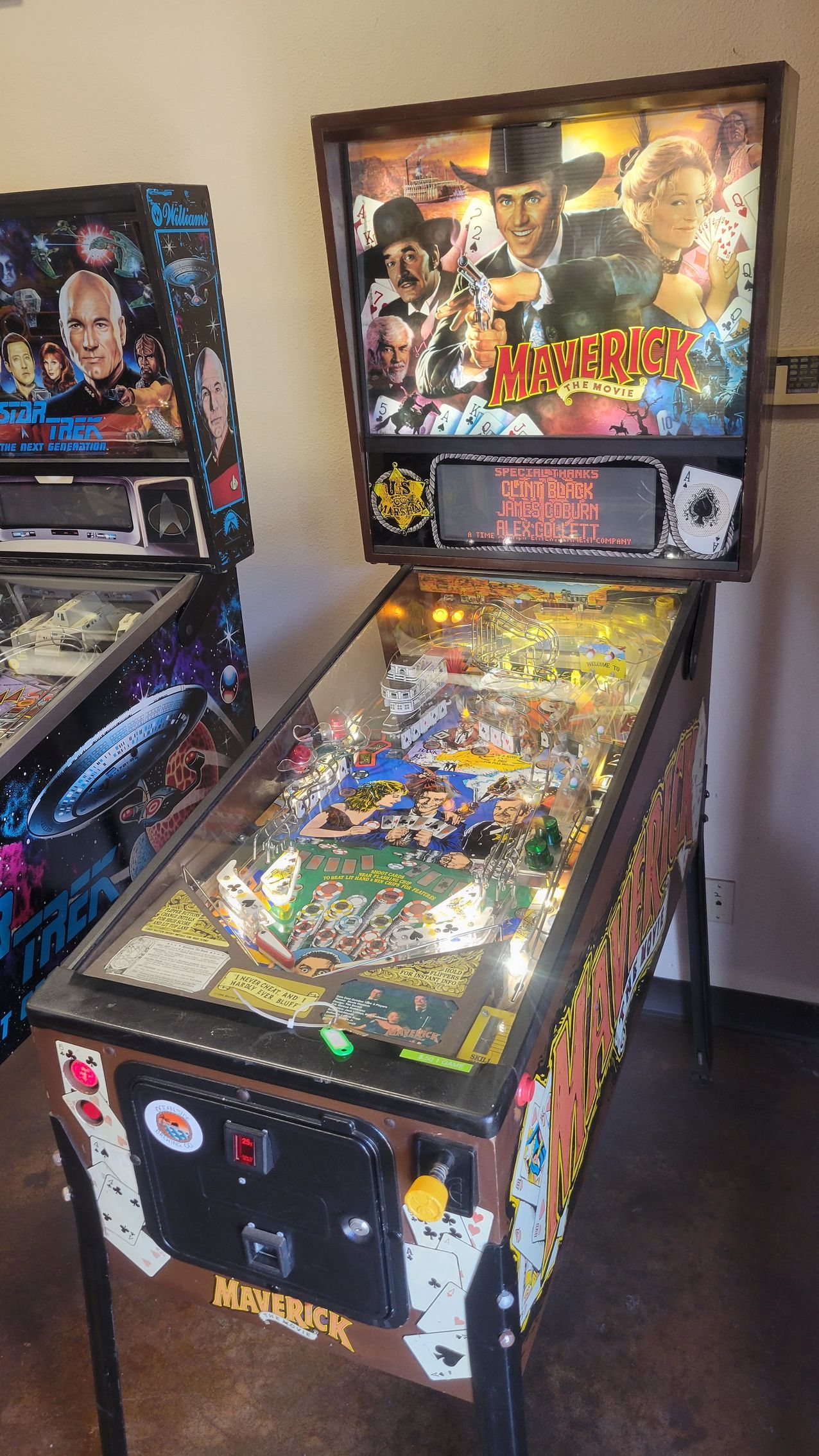 A pinball machine is sitting in a room next to another pinball machine.