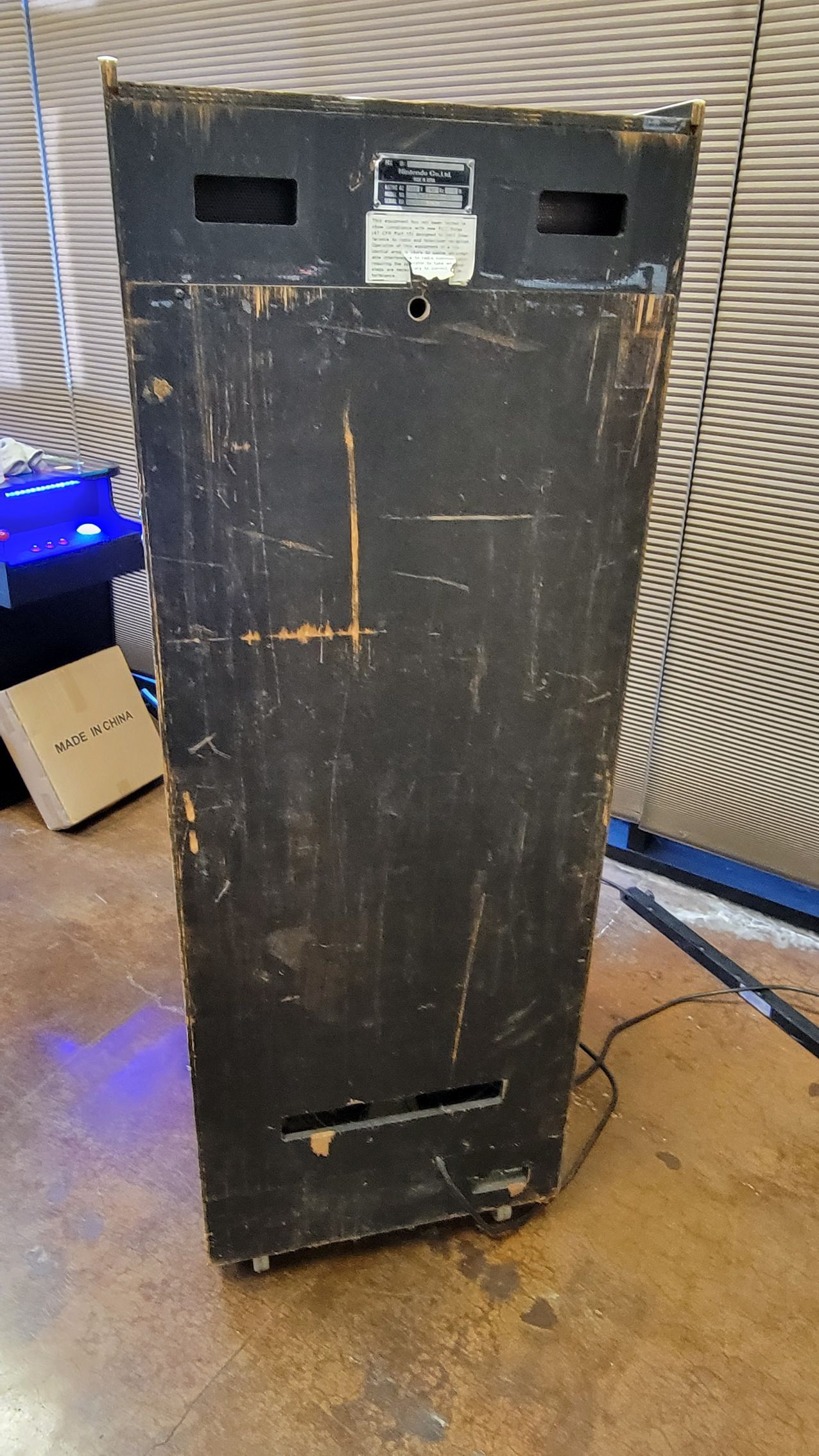 The back of a speaker is sitting on a wooden floor.