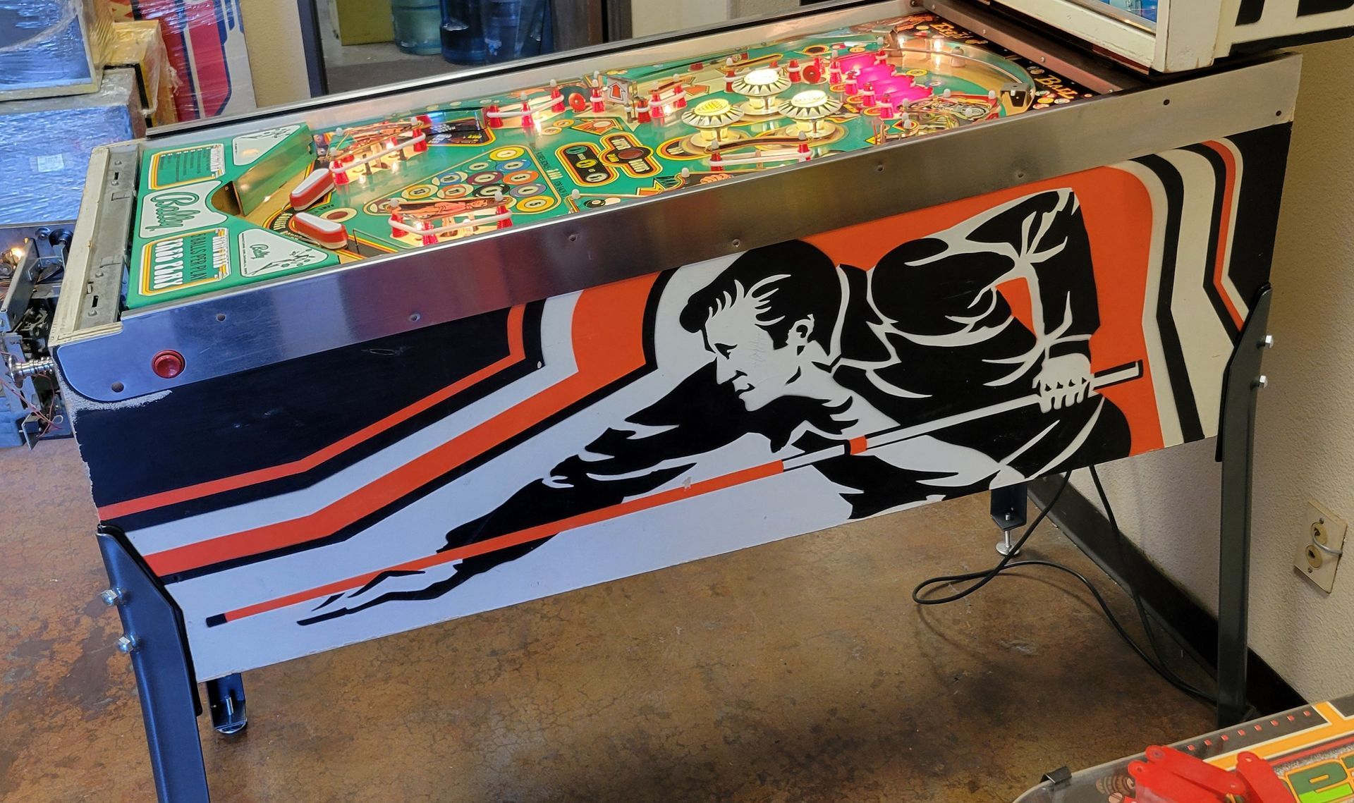 A pinball machine with a man holding a stick on it