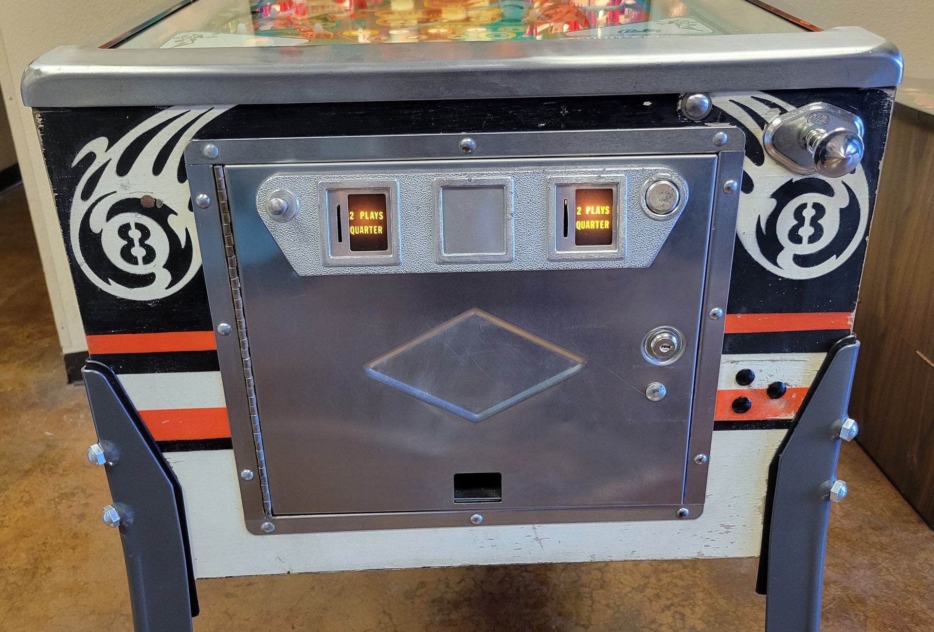 A pinball machine is sitting on a wooden floor.