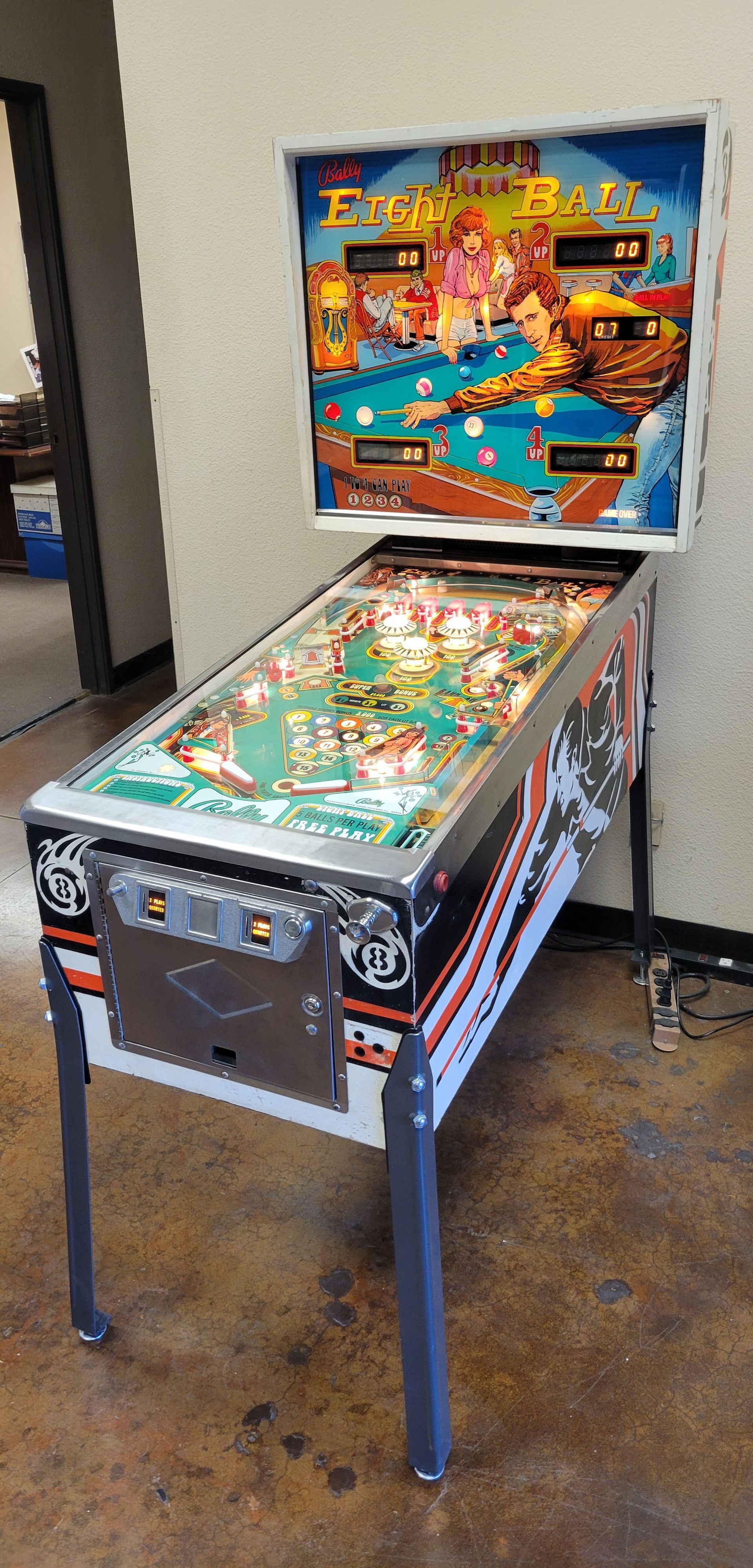 A pinball machine is sitting on a concrete floor in a room.