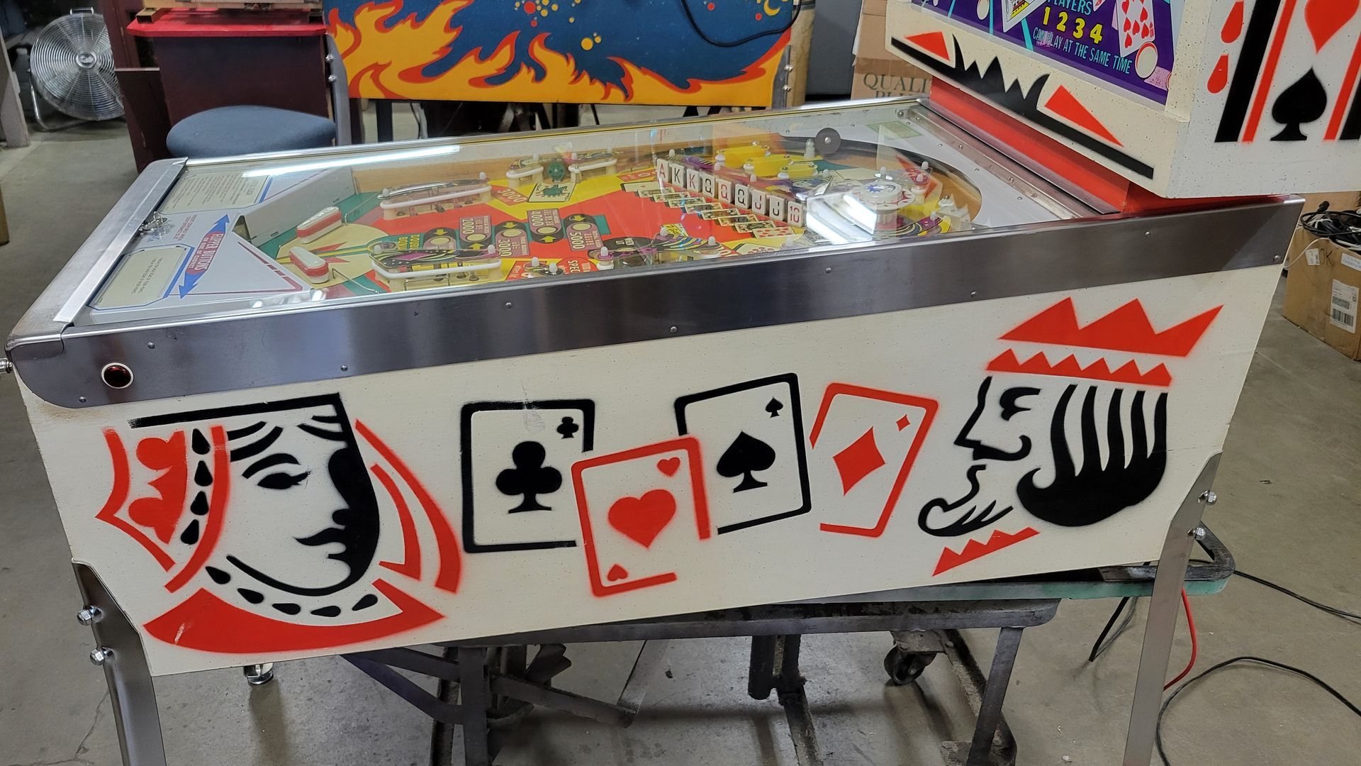 A pinball machine with playing cards painted on it