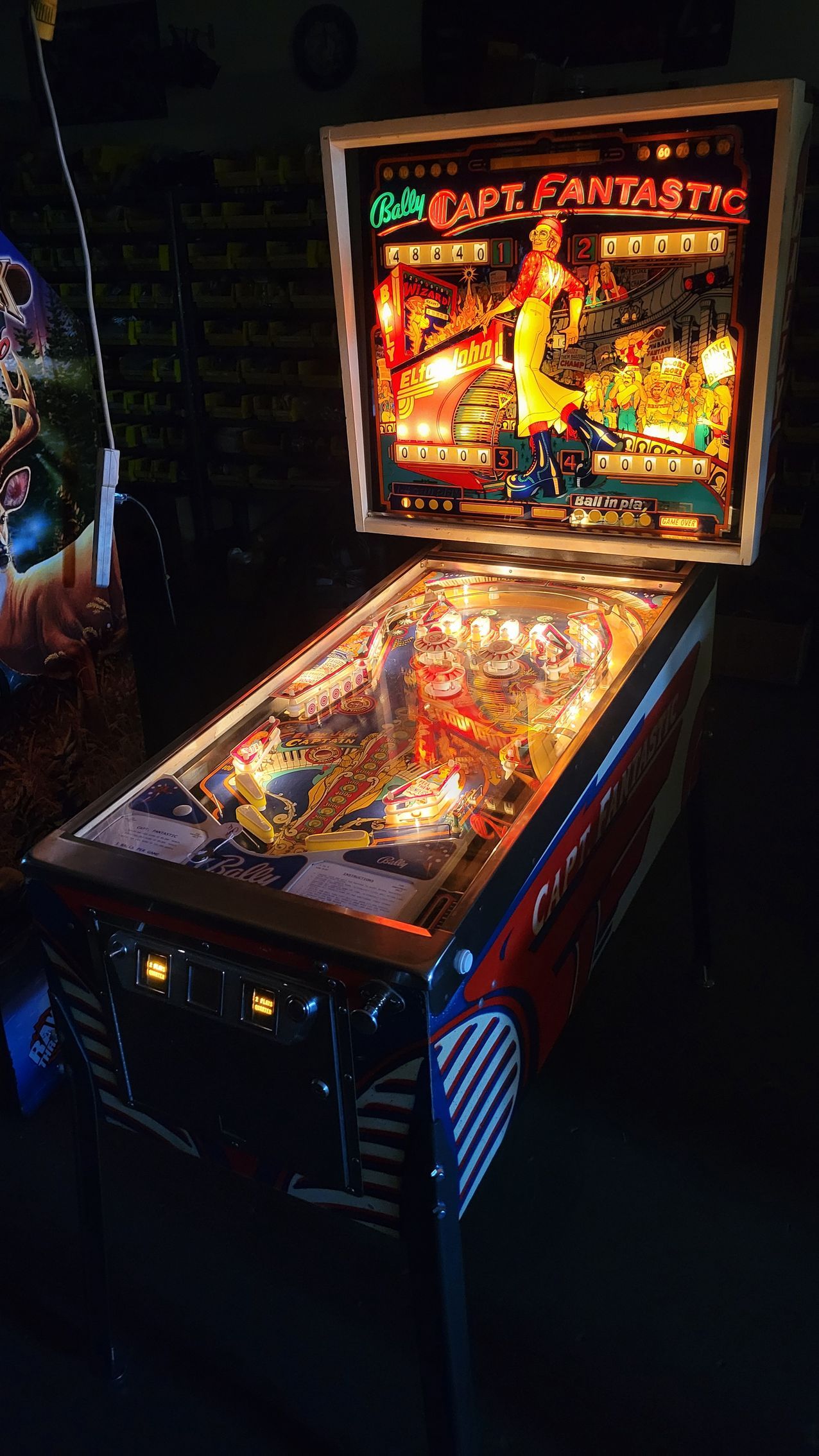 A pinball machine is sitting on a table in a dark room.