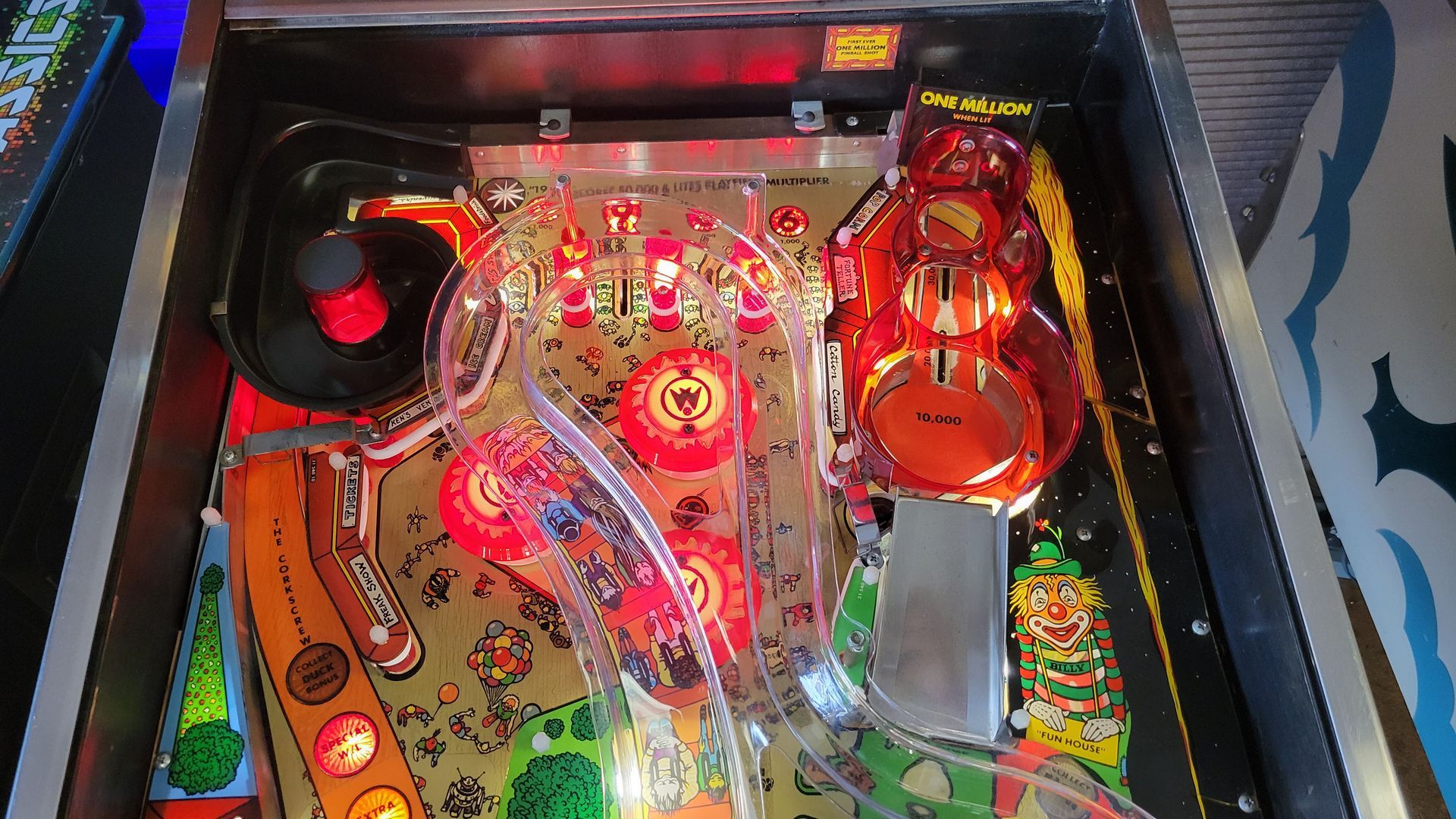 The inside of a pinball machine with a red ball coming out of it.