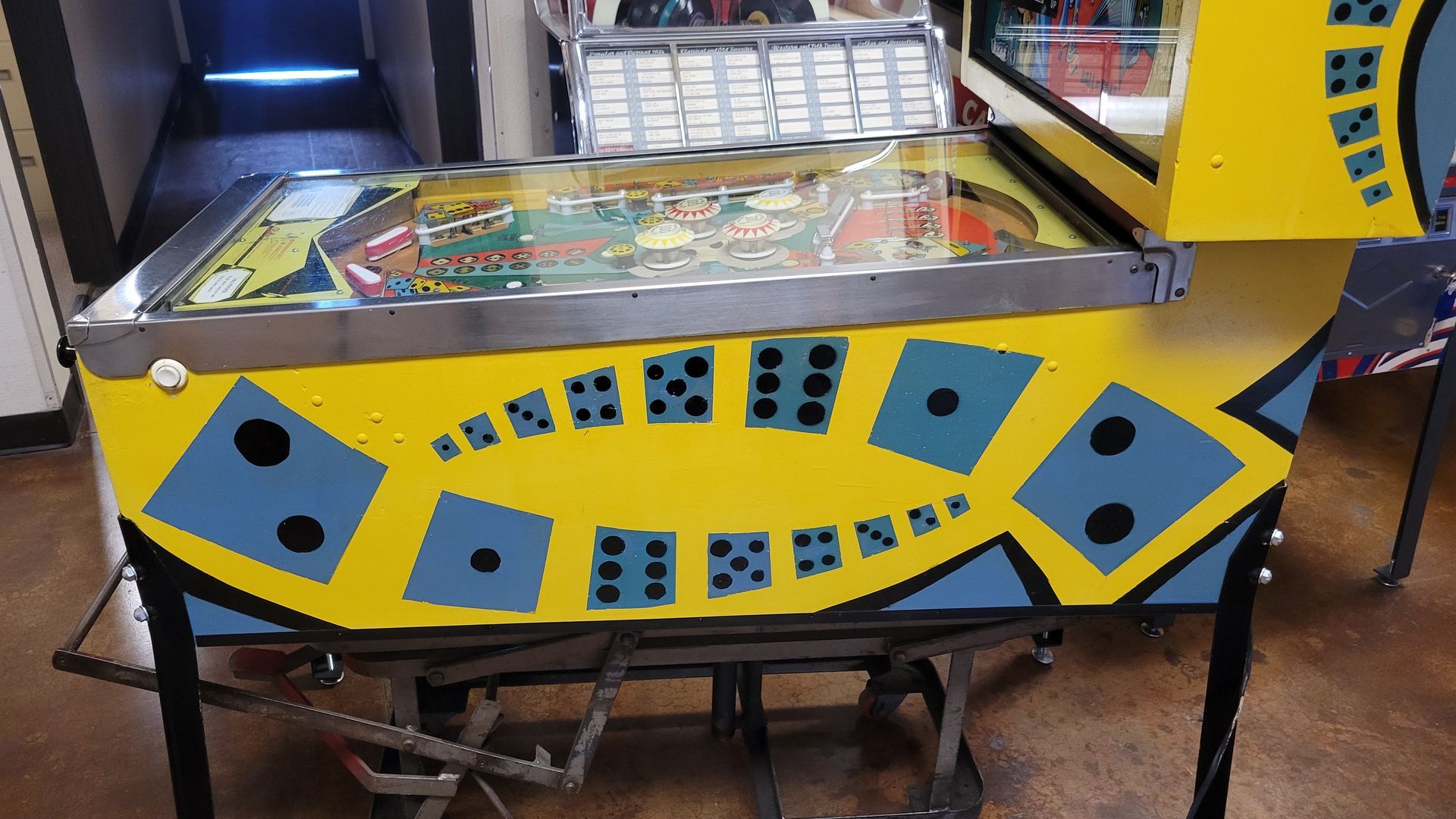 A yellow and blue pinball machine with dice on it