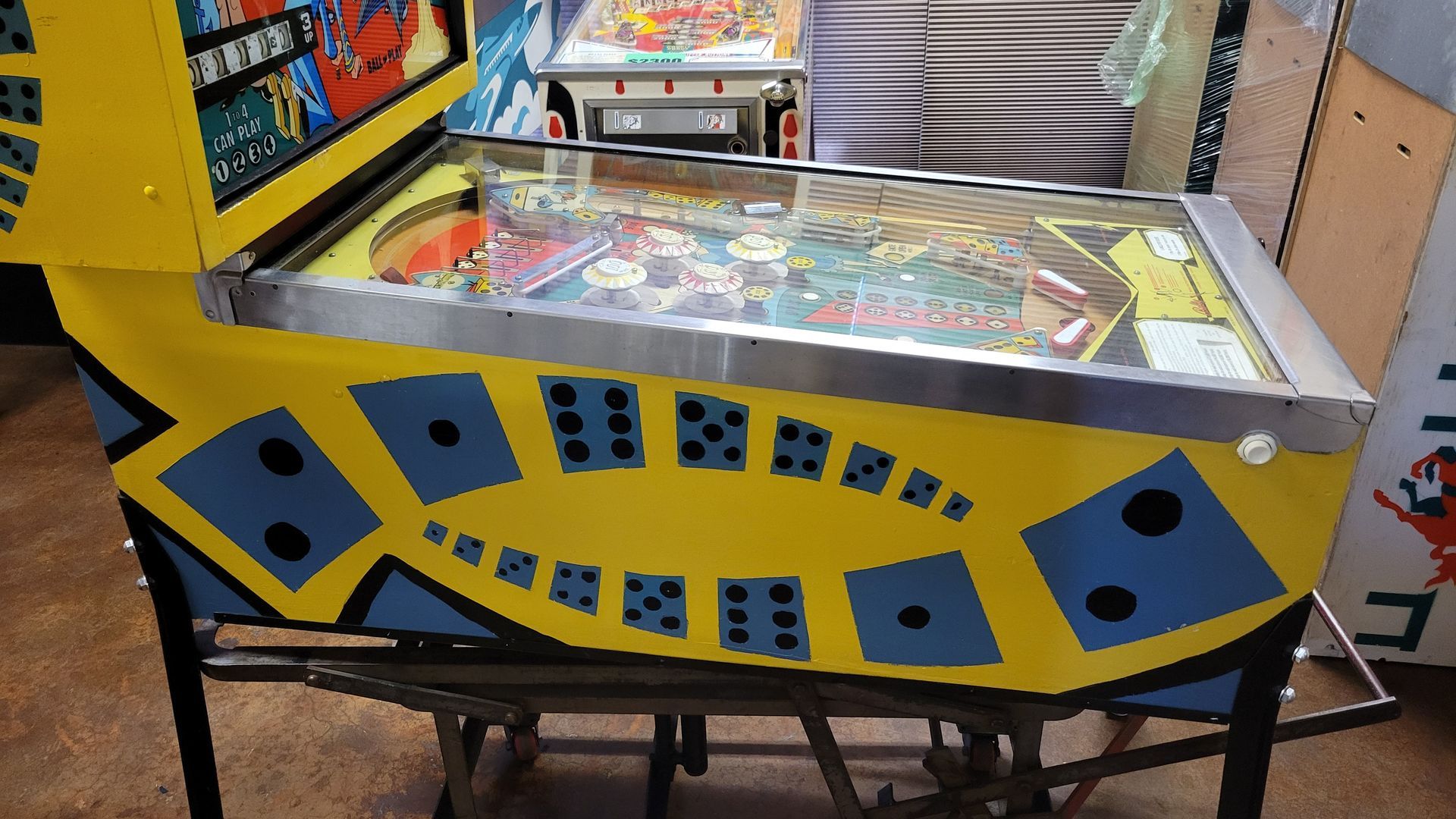 A yellow and blue pinball machine with dice on it