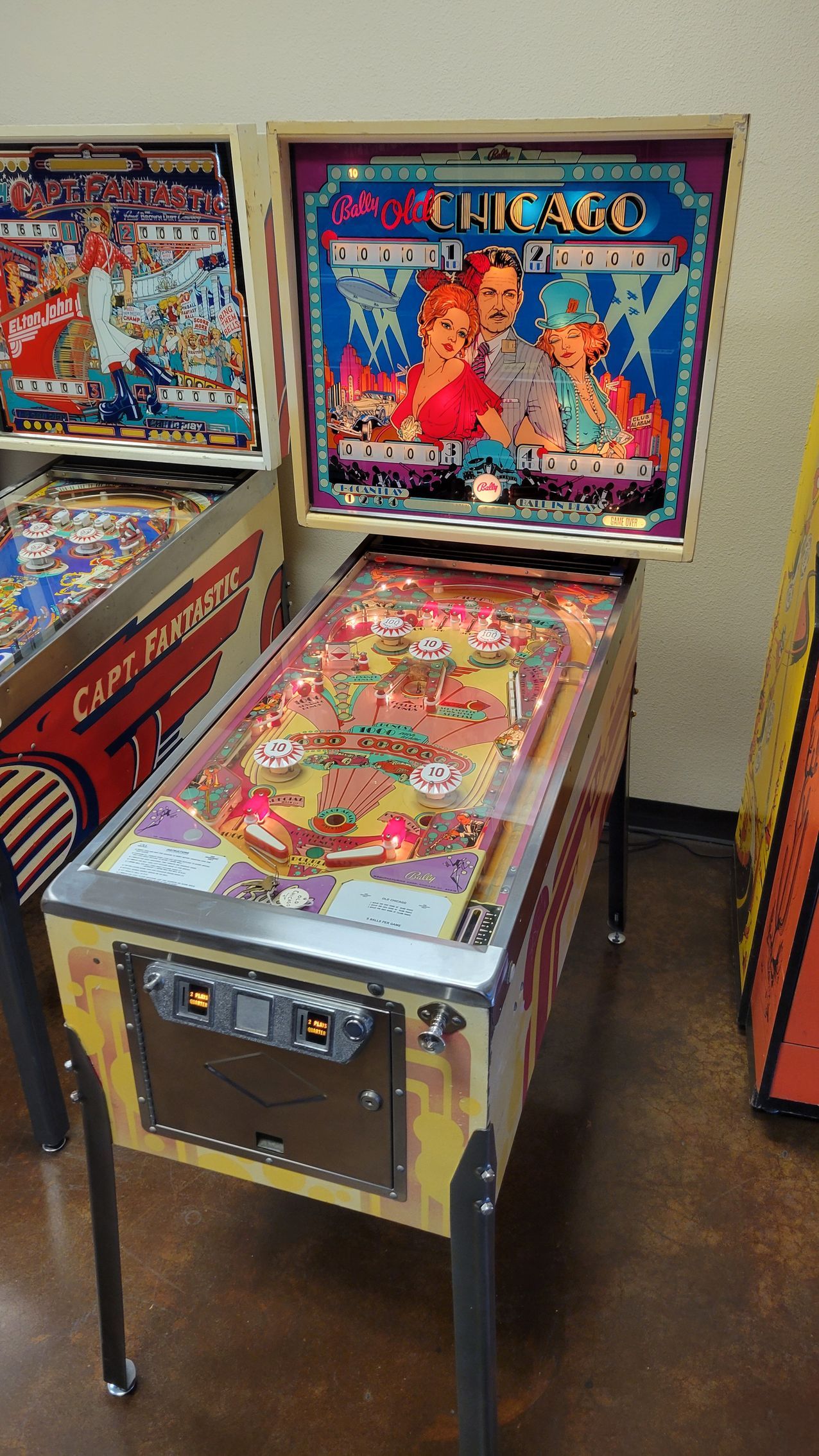 A pinball machine is sitting on a wooden floor in a room.