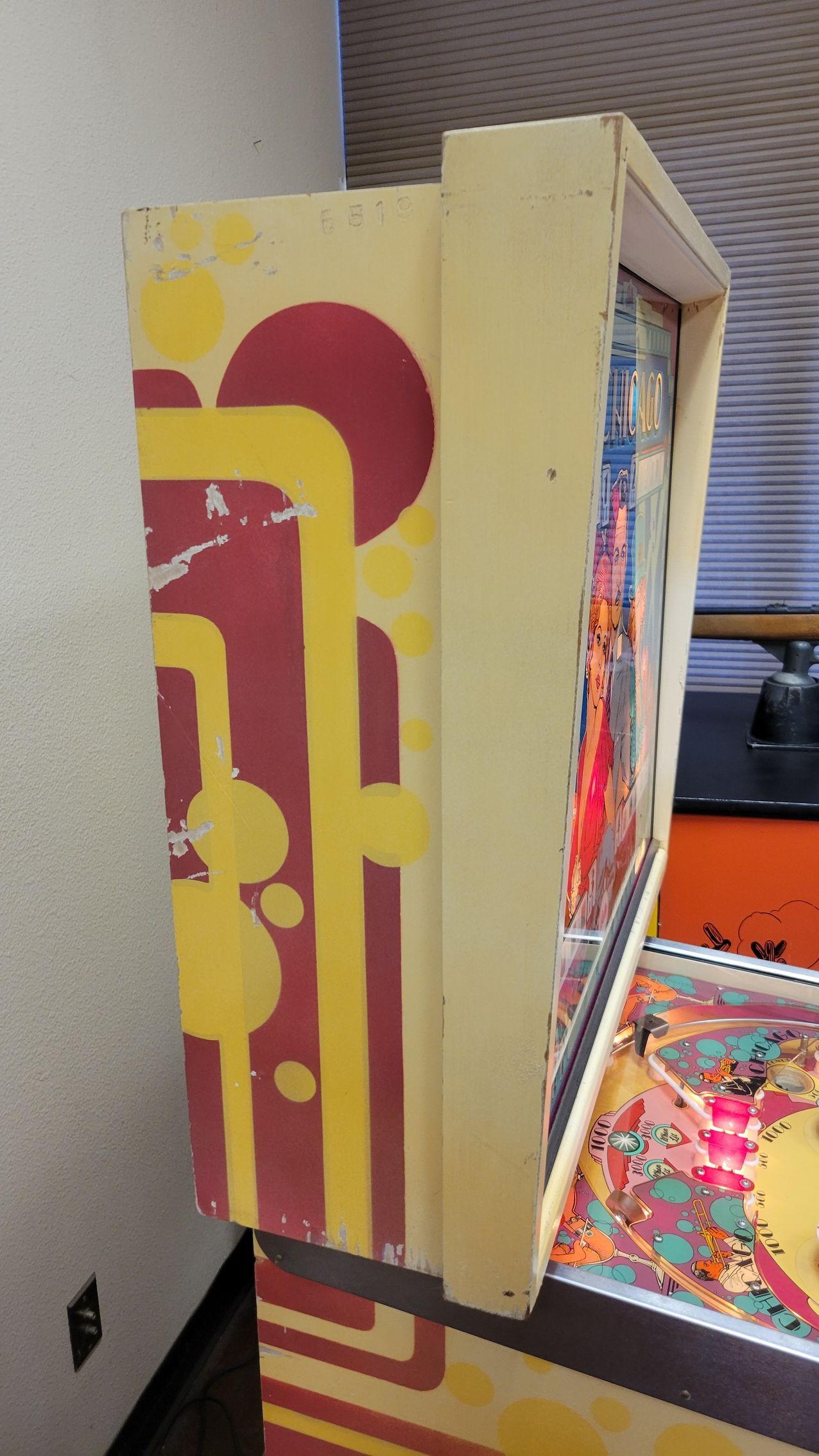 A pinball machine is sitting in a room next to a wall.