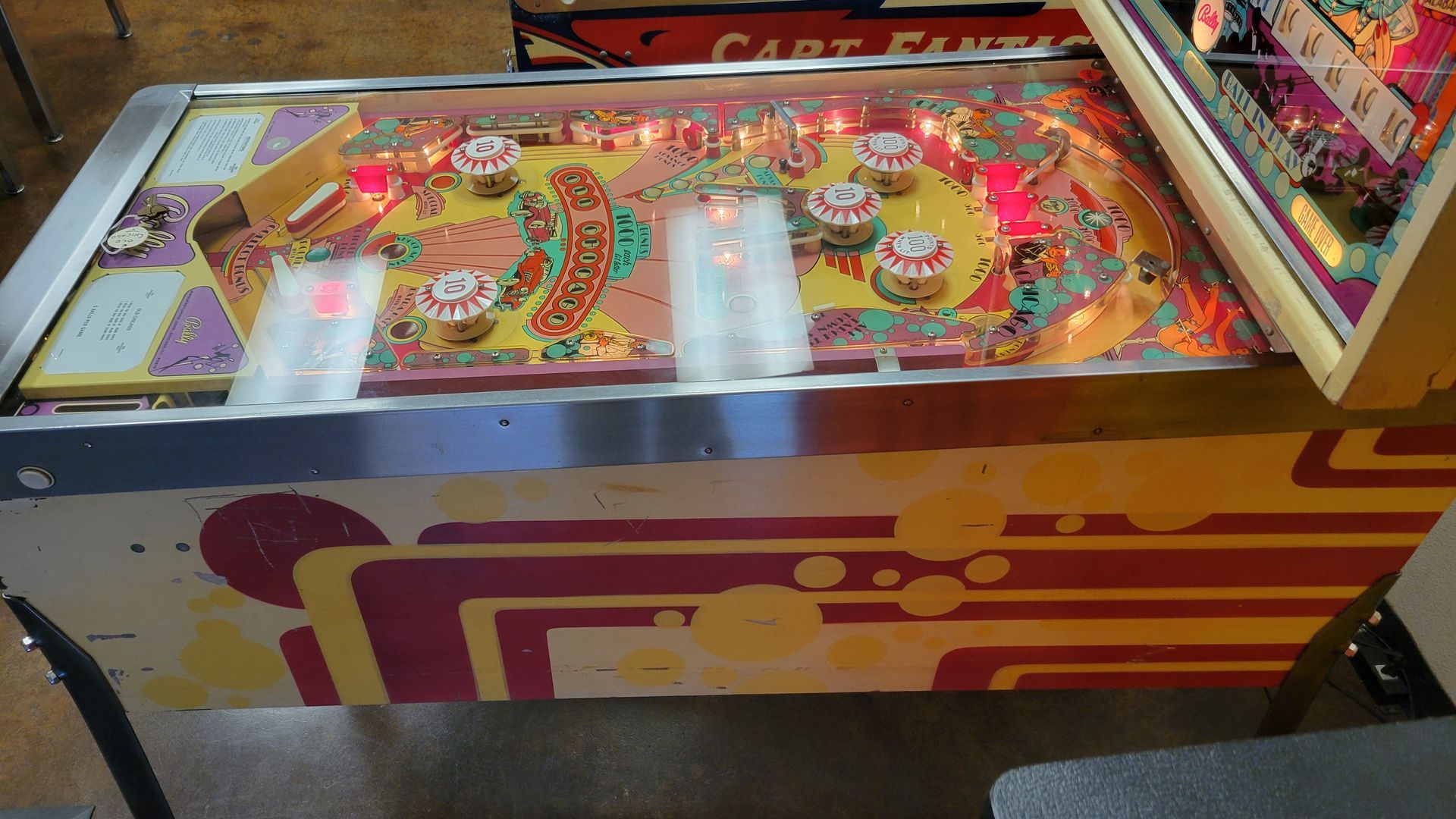 A pinball machine is sitting on a table in a room.