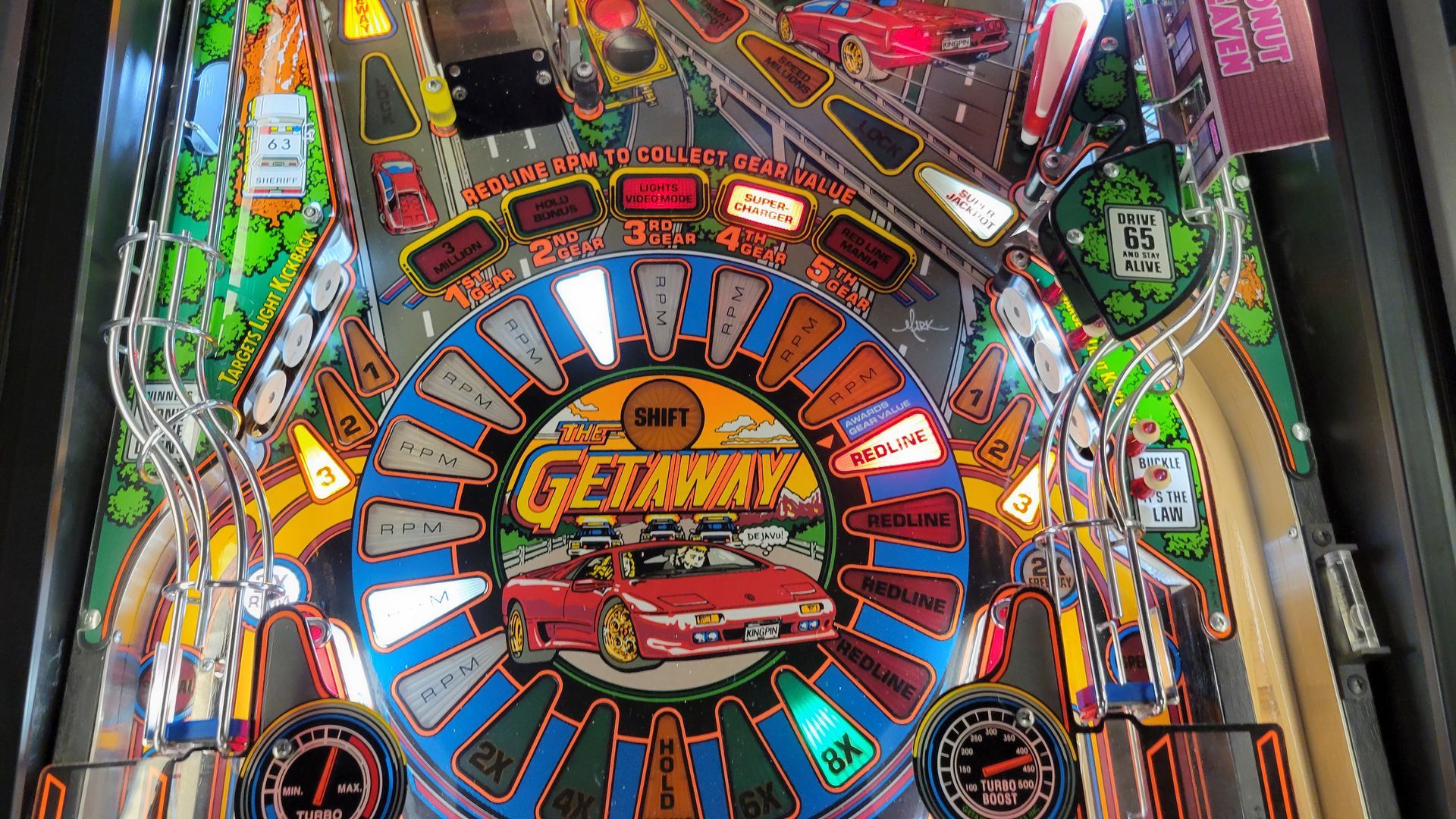 A close up of a pinball machine with a car on it.