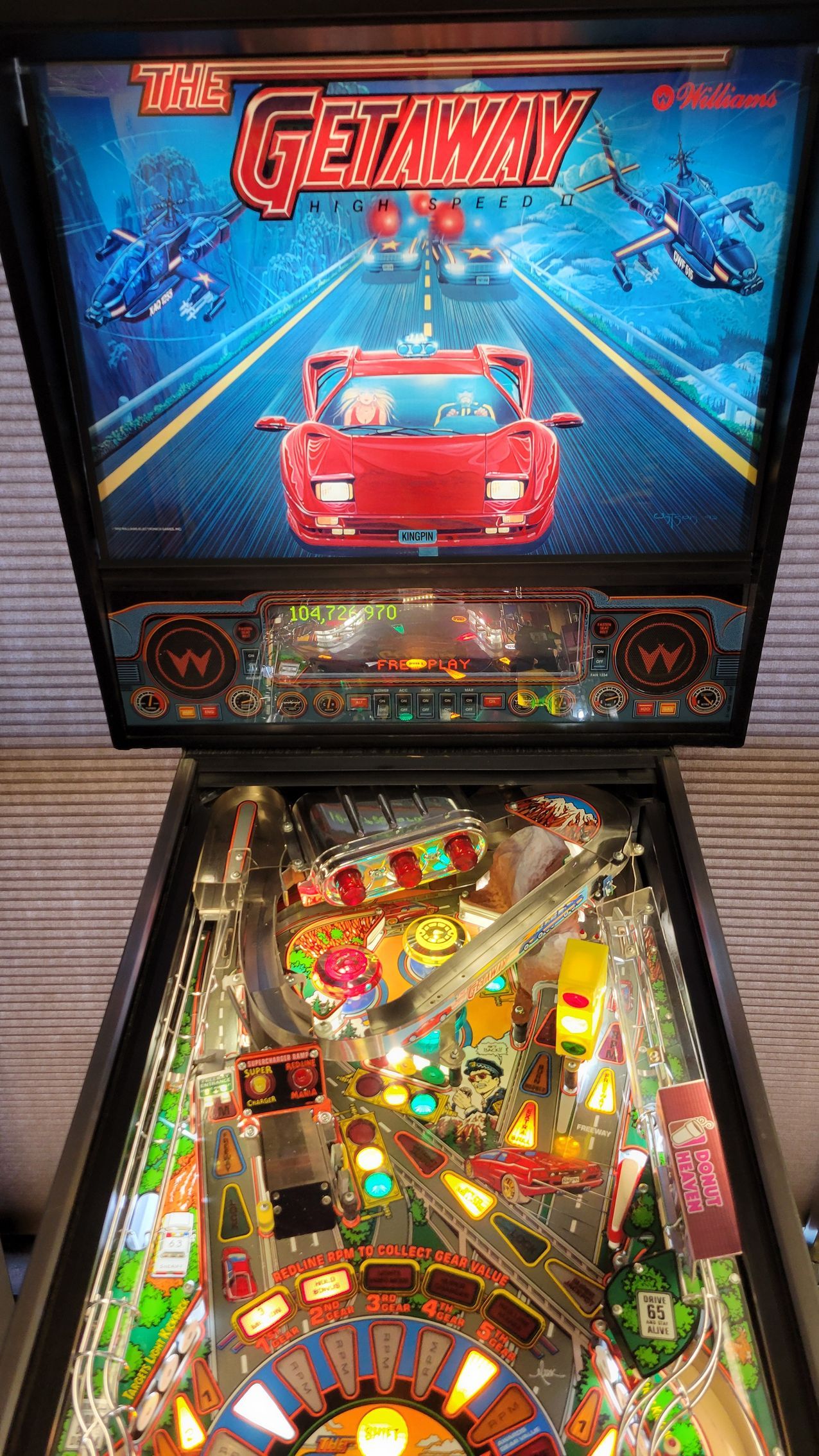 A pinball machine with a red car on the screen.